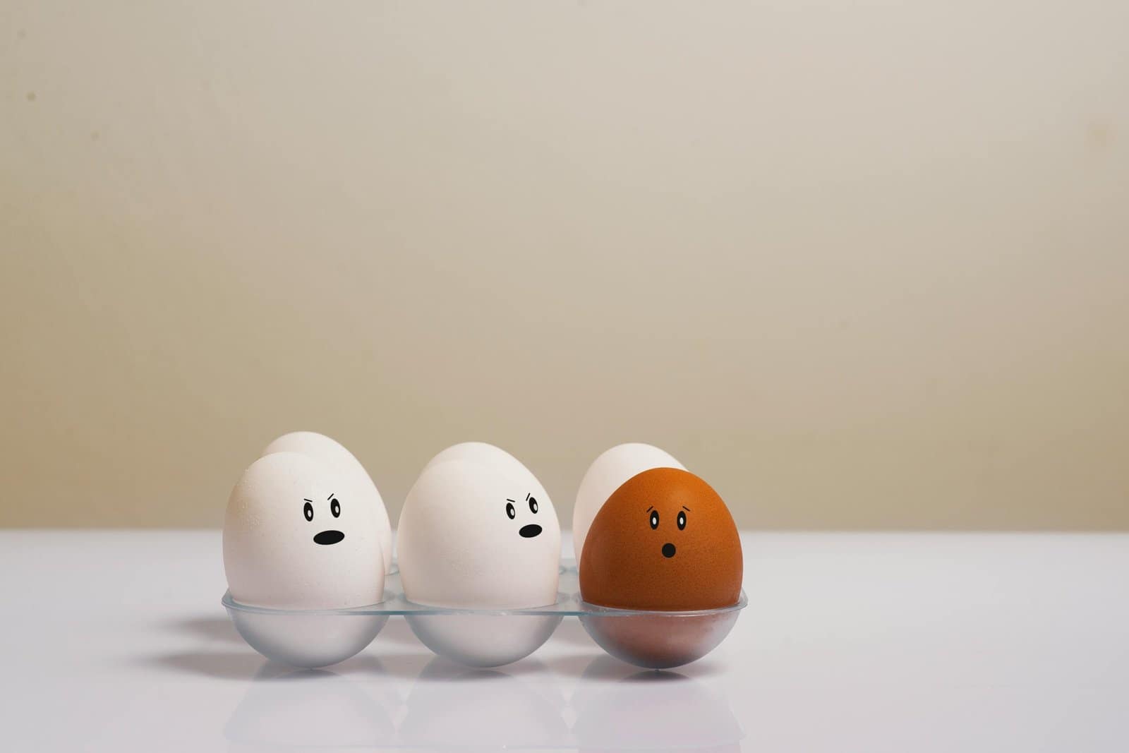 A creative depiction of eggs with facial expressions in a tray, symbolizing diversity.