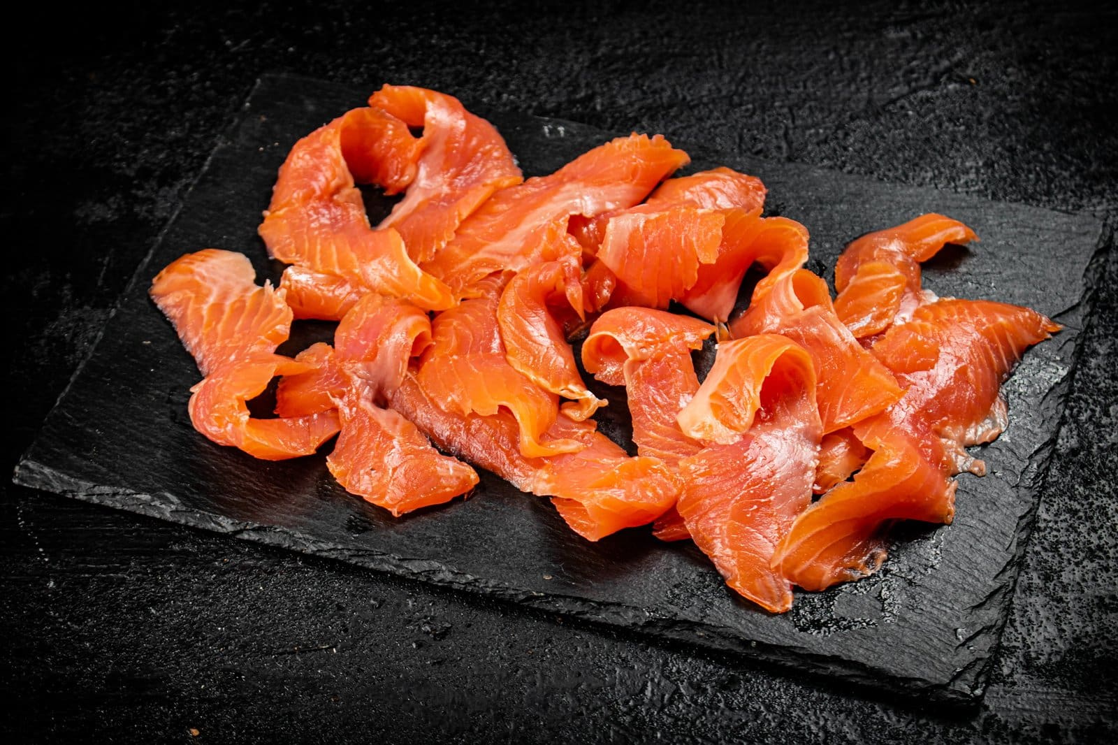 Pieces of salted salmon on a stone board.