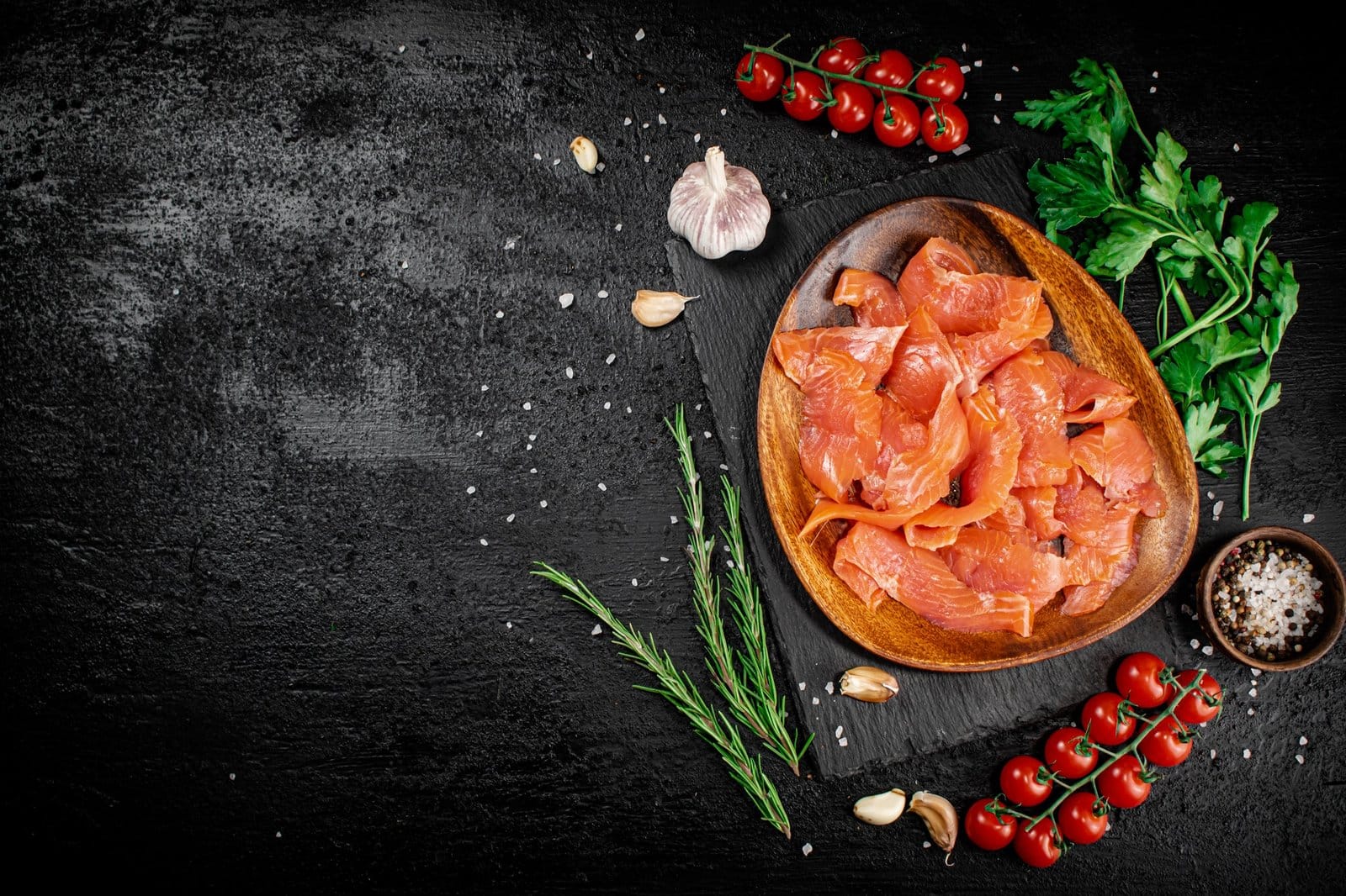 Gesalzener Lachs auf einem Holzteller mit Grünzeug.