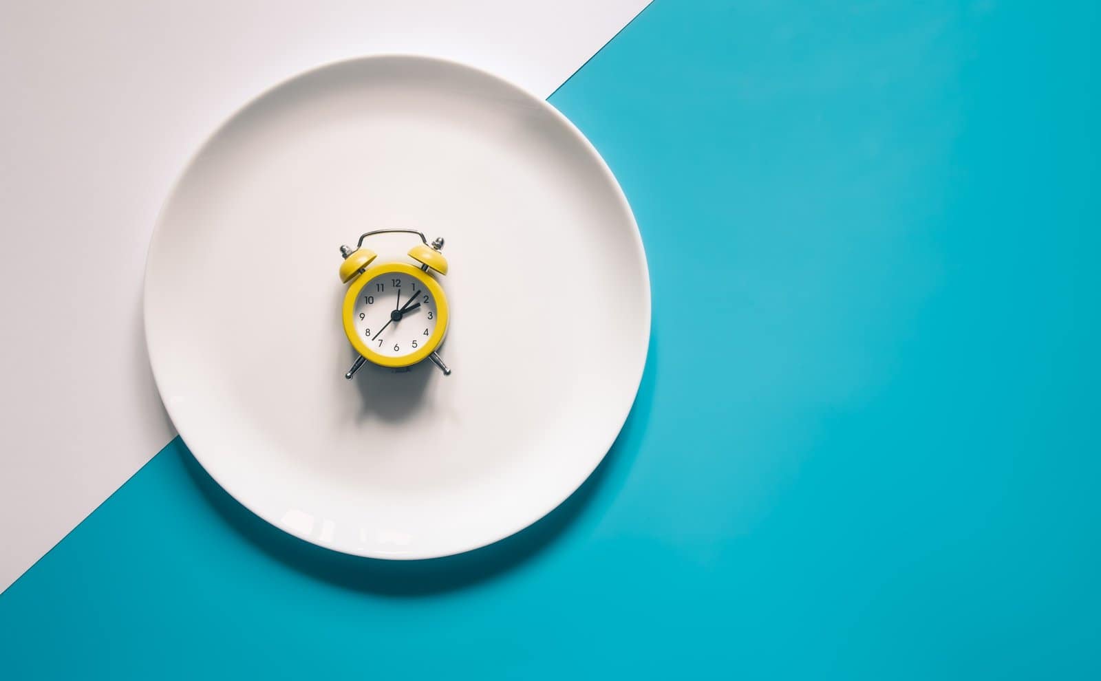 Alarm clock on a white plate on blue background.